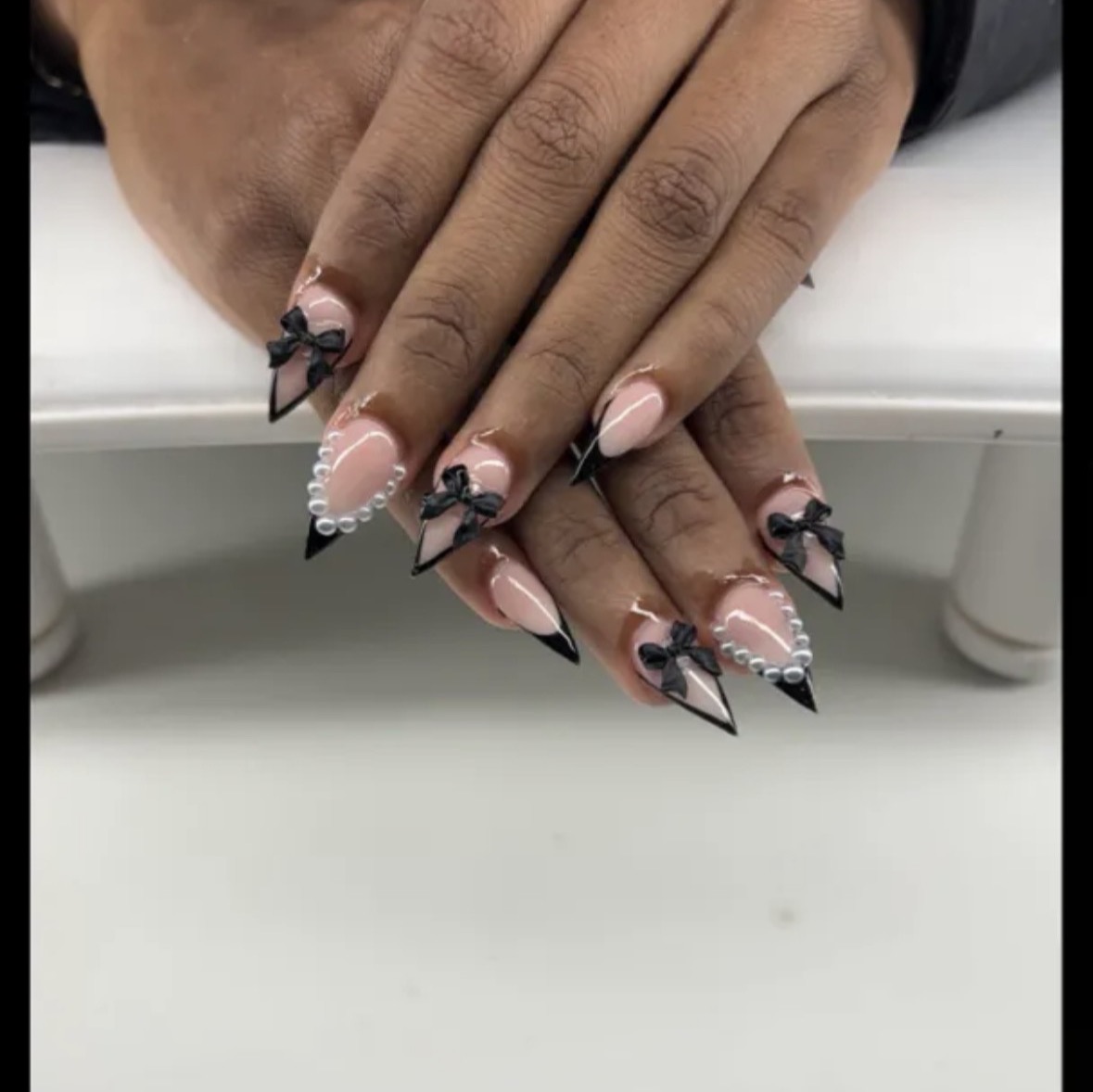 Black bow and pearl stiletto nails by Luxe Nails